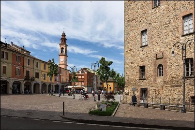 Scorcio di Piazza Umberto I a Pianello Val Tidone. Sulla destra si intravede la Rocca Municipale, sulla sinistra le pittoresche case colorate affacciate sulla piazza e il porticato.